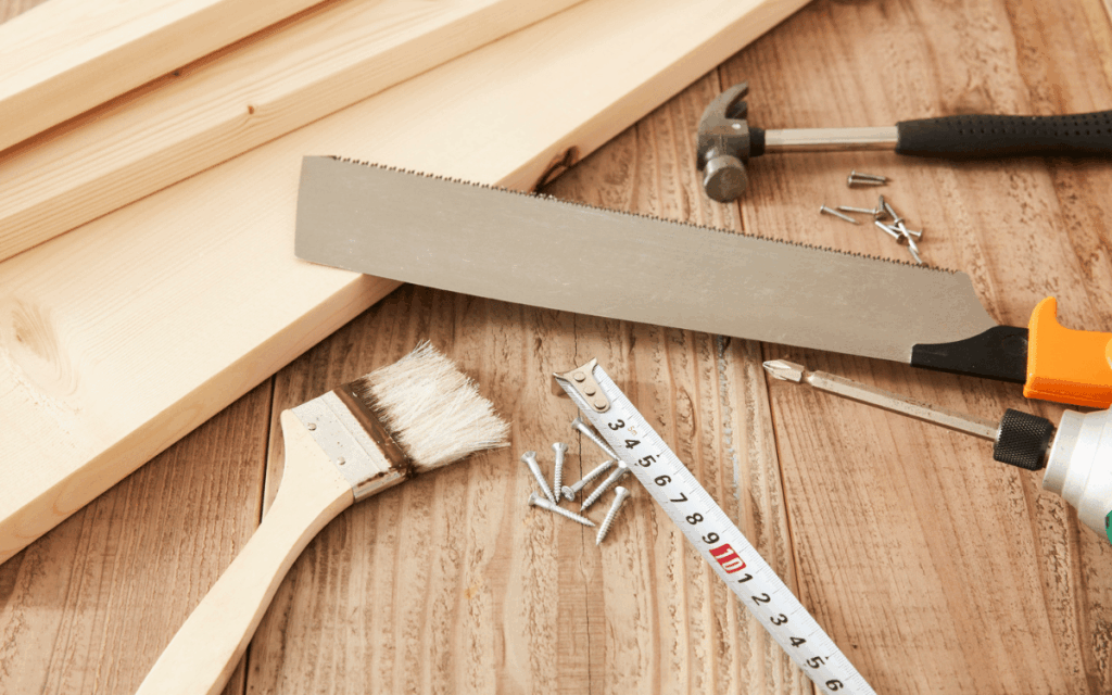 Herramientas de carpintería y materiales de reforma sobre una mesa de trabajo de madera.